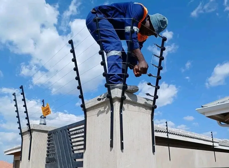 Technician installing an electric fence on a perimeter pillar
