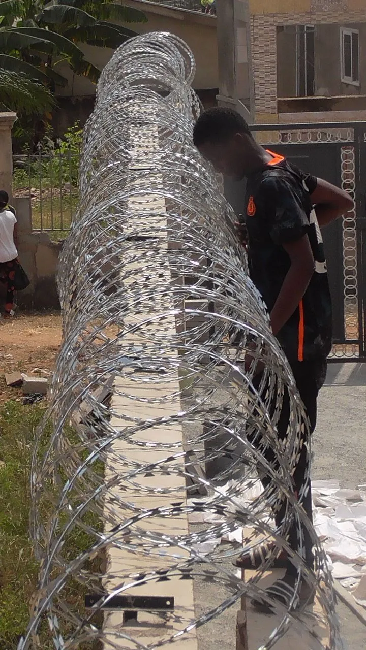 Worker fitting razor wire coil along a perimeter wall